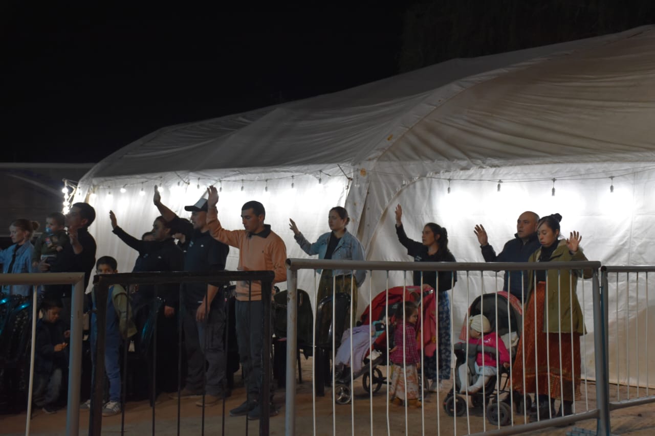 Asistentes con las manos levantadas junto a la carpa durante la campaña.